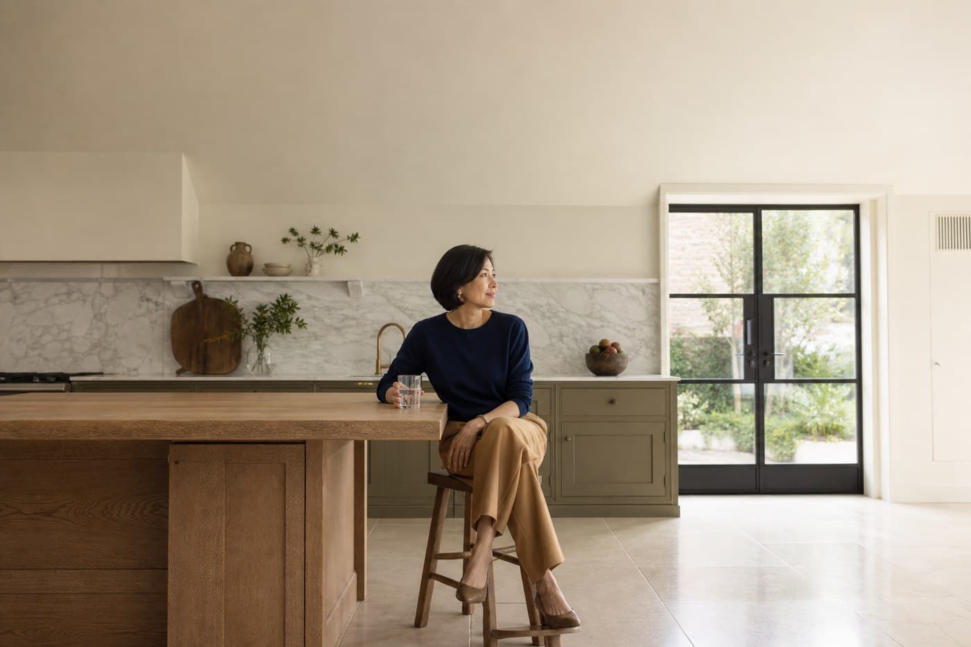 A woman standing in her kitchen with a mug of tea in the small hours, the clock reading just after three.